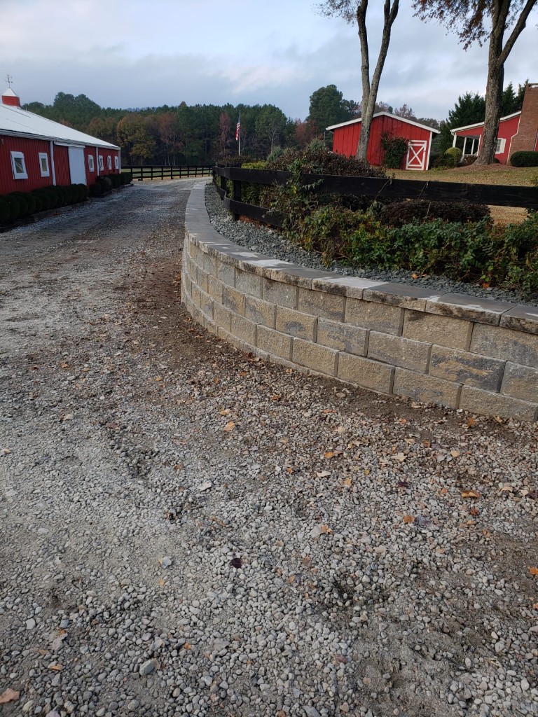 Curved retaining wall installation on gravel driveway edge