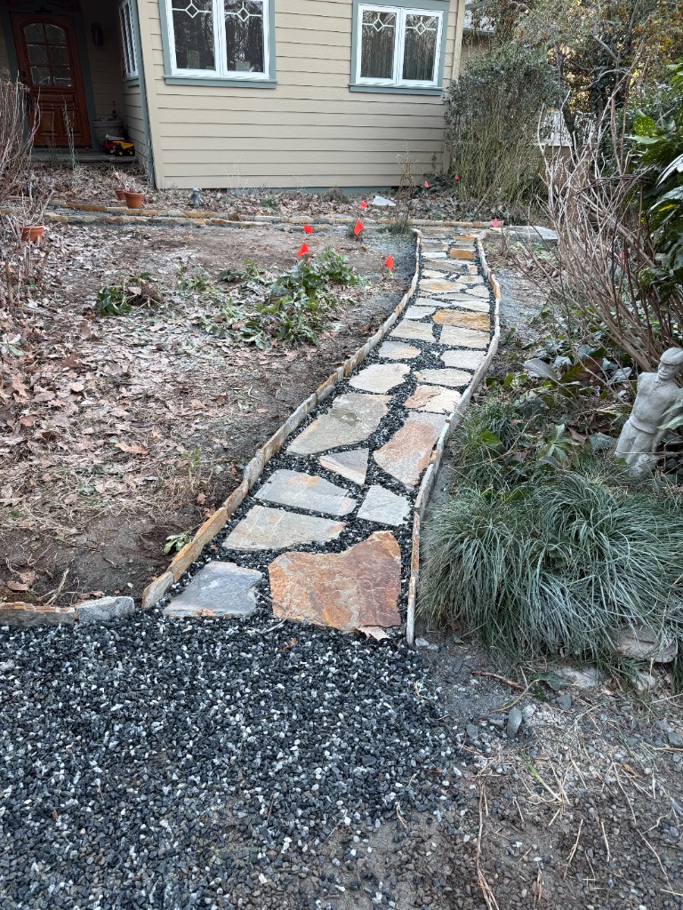 Curved natural stone walkway with dark gravel joints leading to home entry